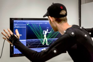 男人看着屏幕上模拟的数字，举起的手连接在电线上