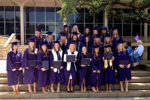 毕业典礼后，一群穿着紫色长袍的室内设计专业学生在台阶上手持毕业证书