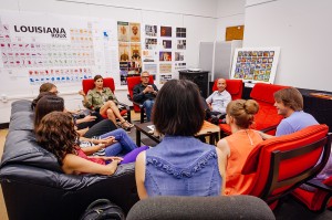 学生们坐在红椅子上，围着来访的艺术家。